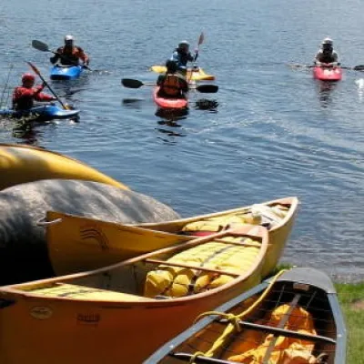 view of canoes on shore and people in kayaks in the water
