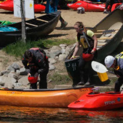 people getting into their kayaks and canoe on shore