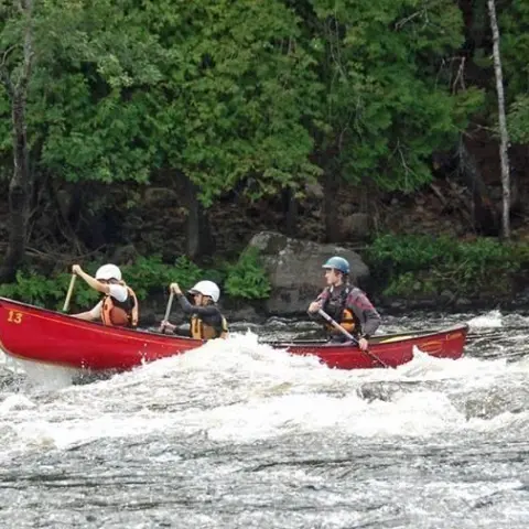3 people in one big red canoe