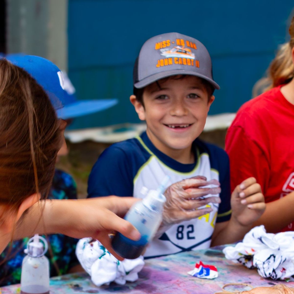 Kids engage in a colorful tie-dye activity at a table, smiling and focused.