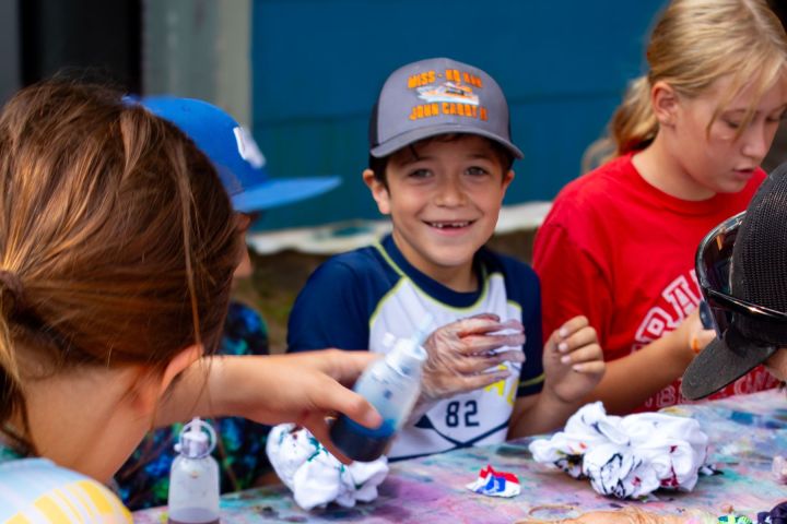 Kids engage in a colorful tie-dye activity at a table, smiling and focused.