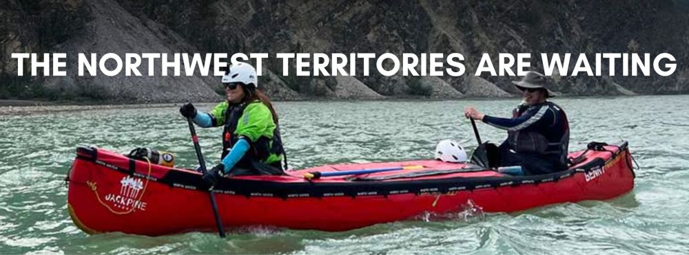 Two people canoeing in a river with text: 'The Northwest Territories are waiting'.