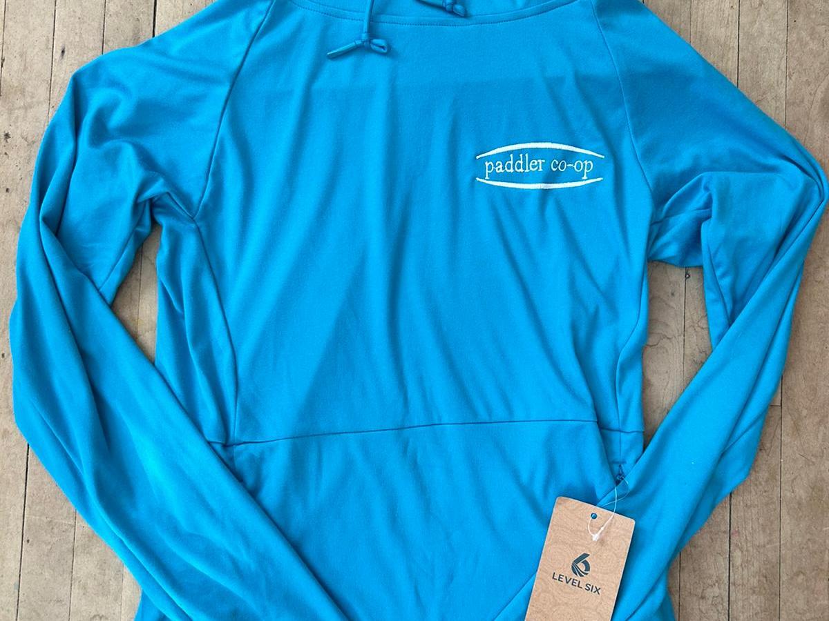 Blue hoodie with logo and tag on wooden floor.